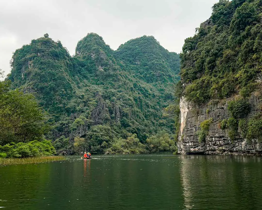 Boot umgeben von riesigen Kalksteinfelsen in Ninh Binh